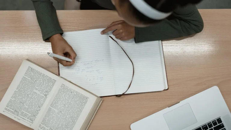 Learner revising for the driving theory test with an open book, notebook and laptop
