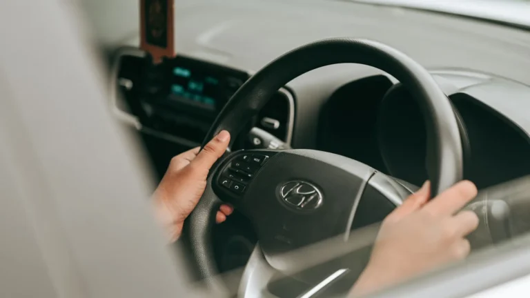 Hands on the steering wheel of a right-hand-drive car with the dashboard controls in view